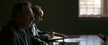 Movie still from “Band of Robbers” (2015), directed by Adam Nee – Two men sitting at a table with papers and a pen; Medium shot, Over the shoulder angle