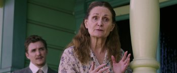 Movie still from “Band of Robbers” (2015), directed by Adam Nee – An older woman is clapping her hands in front of a green wall; Close Up shot, Over the shoulder angle