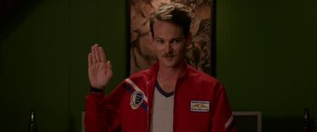 Movie still from “Band of Robbers” (2015), directed by Adam Nee – A man in a red jacket holding up his right hand; Close Up shot, Over the shoulder angle