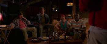 Movie still from “Band of Robbers” (2015), directed by Adam Nee – A group of people sitting around a table with food; Medium shot, High angle