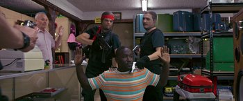 Movie still from “Band of Robbers” (2015), directed by Adam Nee – A group of men standing next to each other in a room; Medium shot, Over the shoulder angle