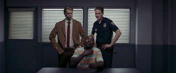 Movie still from “Band of Robbers” (2015), directed by Adam Nee – A man sitting at a table with two other men; Medium shot, Over the shoulder angle