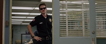 Movie still from “Band of Robbers” (2015), directed by Adam Nee – A police officer standing in front of a door; Medium shot, Low angle
