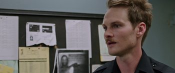 Movie still from “Band of Robbers” (2015), directed by Adam Nee – A person wearing a police uniform; Close Up shot, Over the shoulder angle