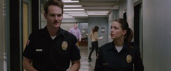 Movie still from “Band of Robbers” (2015), directed by Adam Nee – Two police officers standing next to each other in a hallway; Medium shot, Over the shoulder angle