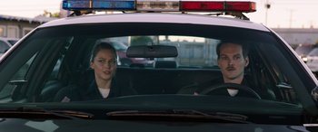 Movie still from “Band of Robbers” (2015), directed by Adam Nee – A man and a woman sitting in the back of a police car; Medium shot, Low angle
