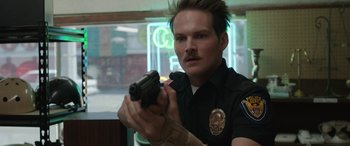Movie still from “Band of Robbers” (2015), directed by Adam Nee – A man in a police uniform holding a gun in his hand; Close Up shot, Low angle