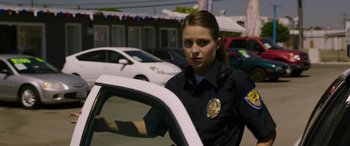 Movie still from “Band of Robbers” (2015), directed by Adam Nee – A police officer standing next to a white car in a parking lot; Close Up shot, Over the shoulder angle