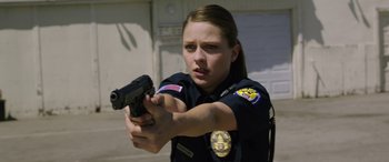 Movie still from “Band of Robbers” (2015), directed by Adam Nee – A police officer holding a gun in her hand; Medium shot, Low angle