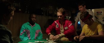 Movie still from “Band of Robbers” (2015), directed by Adam Nee – Two men sitting at a table in front of a pile of money; Medium shot, Over the shoulder angle