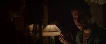Movie still from “Band of Robbers” (2015), directed by Adam Nee – A man holding a piece of paper in front of a lamp; Close Up shot, Over the shoulder angle