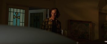 Movie still from “Band of Robbers” (2015), directed by Adam Nee – A man standing in front of a mirror in a dark room; Medium shot, Low angle