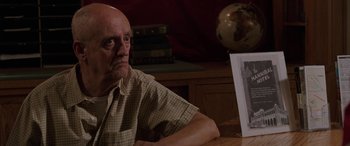 Movie still from “Band of Robbers” (2015), directed by Adam Nee – An older man sitting in front of a picture; Close Up shot, High angle