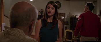 Movie still from “Band of Robbers” (2015), directed by Adam Nee – A woman in a blue dress standing in front of an older man; Medium shot, Over the shoulder angle