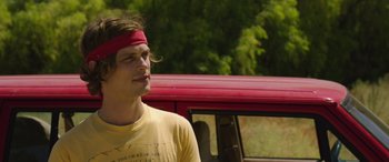 Movie still from “Band of Robbers” (2015), directed by Adam Nee – A young man standing in front of a red truck; Close Up shot, Over the shoulder angle