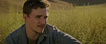 Movie still from “Band of Robbers” (2015), directed by Adam Nee – A person sitting in a grass field; Close Up shot, Over the shoulder angle