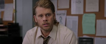 Movie still from “Band of Robbers” (2015), directed by Adam Nee – A man with long blonde hair wearing a shirt and tie; Close Up shot, Over the shoulder angle