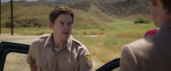 Movie still from “Band of Robbers” (2015), directed by Adam Nee – A man in a uniform sitting in a car; Close Up shot, Over the shoulder angle