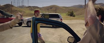 Movie still from “Band of Robbers” (2015), directed by Adam Nee – A person in a vehicle with a red bandana on; Medium shot, Over the shoulder angle