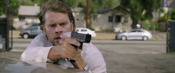 Movie still from “Band of Robbers” (2015), directed by Adam Nee – A man holding a gun while standing in a parking lot; Close Up shot, Over the shoulder angle