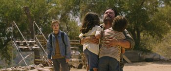 Movie still from “Band of Robbers” (2015), directed by Adam Nee – A man and two children hugging each other in a field; Medium shot, Low angle