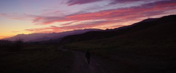 Movie still from “Band of Robbers” (2015), directed by Adam Nee – A person walking down a dirt road at sunset; Extreme Wide shot, High angle