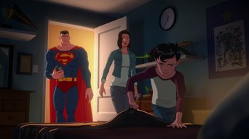 Movie still from “Batman and Superman: Battle of the Super Sons” (2022), directed by Matt Peters – A man and a woman standing next to a man in a room; Wide shot, High angle