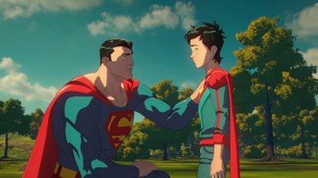 Movie still from “Batman and Superman: Battle of the Super Sons” (2022), directed by Matt Peters – A man and a boy in a field with trees in the background; Medium shot, Over the shoulder angle