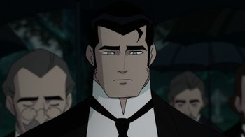 Movie still from “Batman: Gotham by Gaslight” (2018), directed by Sam Liu – A man in a suit and tie standing in front of other men; Close Up shot, Over the shoulder angle