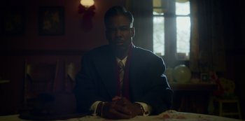Movie still from “Fargo” (2014), created by Noah Hawley – A man sitting at a table in a room; Medium shot, Low angle