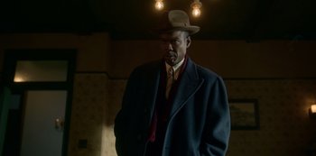 Movie still from “Fargo” (2014), created by Noah Hawley – A man wearing a hat and a coat; Medium shot, Low angle