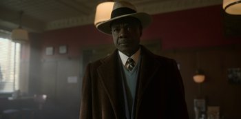 Movie still from “Fargo” (2014), created by Noah Hawley – A man wearing a hat and a coat; Medium shot, Low angle
