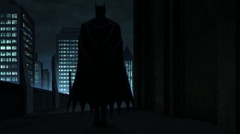 Movie still from “Batman: The Killing Joke” (2016), directed by Sam Liu – A batman standing in front of a building at night; Wide shot, Low angle