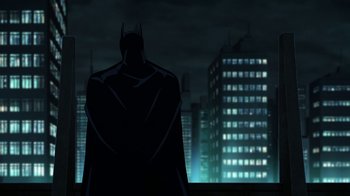 Movie still from “Batman: The Killing Joke” (2016), directed by Sam Liu – A batman standing in front of a city at night; Wide shot, Low angle