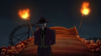 Movie still from “Batman: The Killing Joke” (2016), directed by Sam Liu – A man wearing a hat standing in front of an amusement park; Wide shot, Low angle