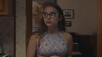 Movie still from “Beach Rats” (2017), directed by Eliza Hittman – A woman with glasses is looking into the distance; Medium shot, Over the shoulder angle