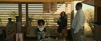 Movie still from “Beast” (2022), directed by Baltasar Kormákur – Two women are sitting on a bench and one of them is taking a picture; Medium shot, Low angle