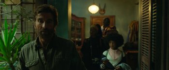 Movie still from “Beast” (2022), directed by Baltasar Kormákur – A group of people standing in a living room; Medium shot, Over the shoulder angle