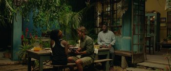 Movie still from “Beast” (2022), directed by Baltasar Kormákur – A group of people sitting around a wooden bench; Wide shot, Over the shoulder angle