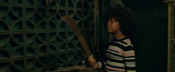 Movie still from “Beast” (2022), directed by Baltasar Kormákur – A person holding a large saw in their hands; Medium shot, Over the shoulder angle