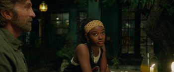 Movie still from “Beast” (2022), directed by Baltasar Kormákur – A woman with a headband sitting on the ground; Close Up shot, Over the shoulder angle