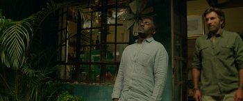 Movie still from “Beast” (2022), directed by Baltasar Kormákur – A man standing in front of a building looking up; Medium shot, Low angle