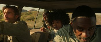 Movie still from “Beast” (2022), directed by Baltasar Kormákur – Two young people sitting in the back seat of a car; Close Up shot, Over the shoulder angle