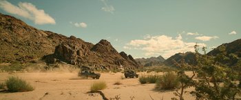 Movie still from “Beast” (2022), directed by Baltasar Kormákur – A couple of trucks driving down a dirt road; Extreme Wide shot, High angle