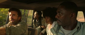 Movie still from “Beast” (2022), directed by Baltasar Kormákur – A group of people sitting in the back of a car; Medium shot, Over the shoulder angle