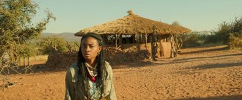 Movie still from “Beast” (2022), directed by Baltasar Kormákur – A woman standing in front of a hut in the desert; Medium shot, Low angle