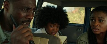 Movie still from “Beast” (2022), directed by Baltasar Kormákur – A young girl with a large afro sitting in the back seat of a car; Close Up shot, Over the shoulder angle