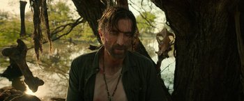 Movie still from “Beast” (2022), directed by Baltasar Kormákur – A man with a beard is standing under a tree; Close Up shot, Low angle