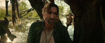 Movie still from “Beast” (2022), directed by Baltasar Kormákur – A man with a beard is standing next to a tree; Close Up shot, Over the shoulder angle