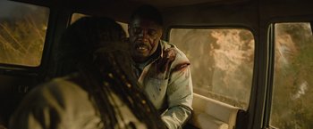 Movie still from “Beast” (2022), directed by Baltasar Kormákur – A man in a car with blood all over his face; Medium shot, Over the shoulder angle